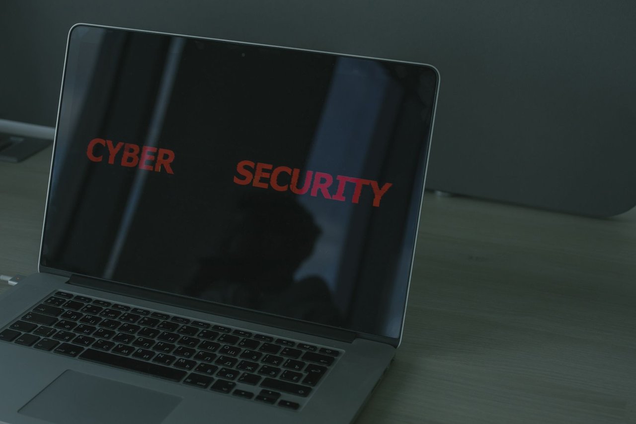 Laptop exibindo conteúdo relacionado à segurança cibernética em uma tela escura.