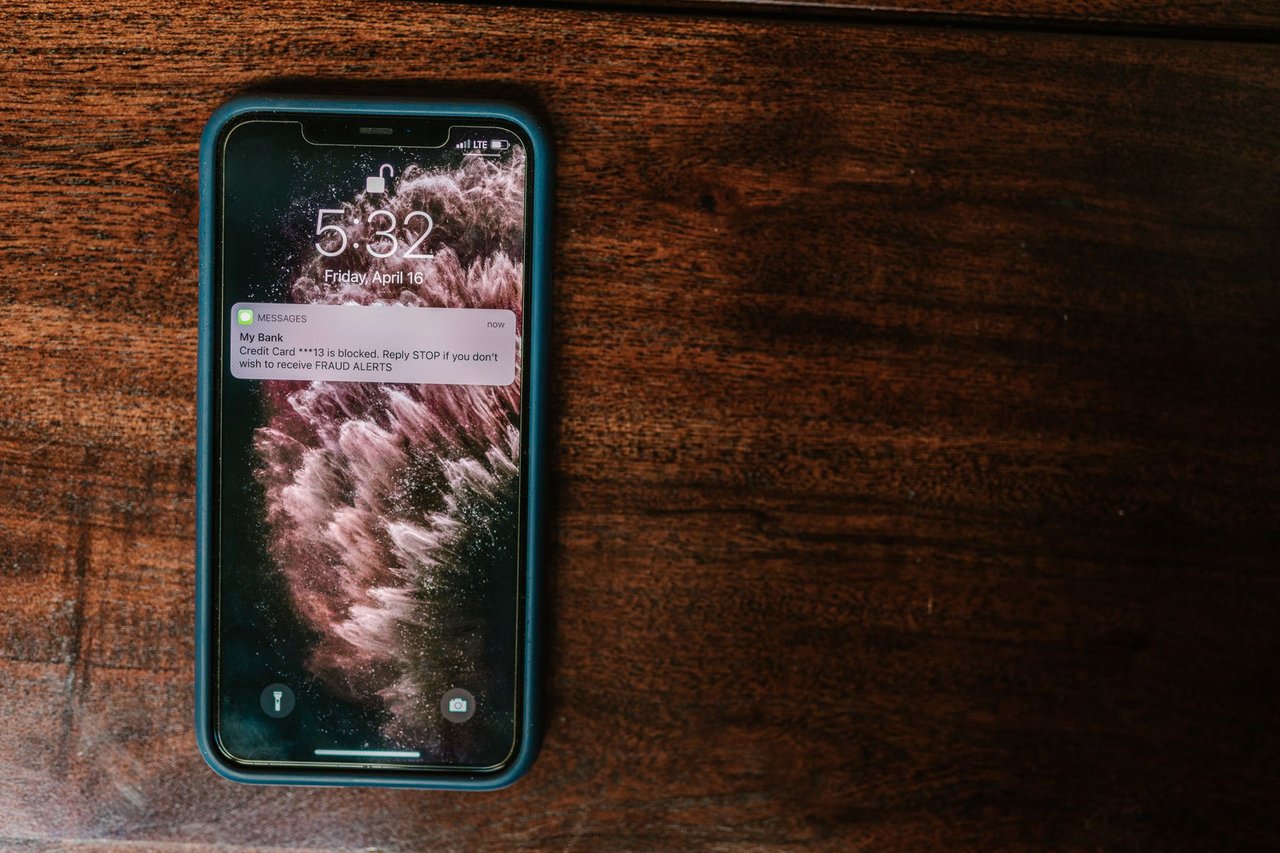 Celular exibindo uma notificação de alerta bancário sobre uma superfície de madeira
