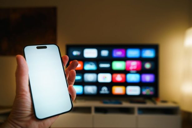 Smartphone em primeiro plano diante de uma televisão inteligente com aplicativos exibidos em uma sala de estar.